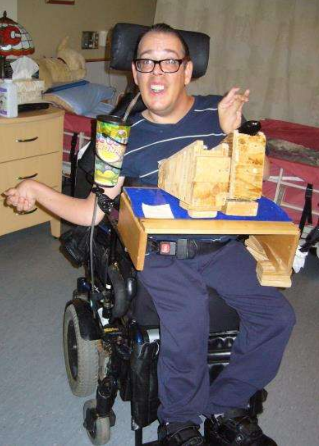 Man wearing glasses in a wheelchair working on a craft project