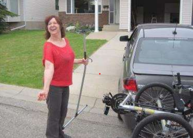 Woman in a red shirt smiling after she secured her bicycle to a car