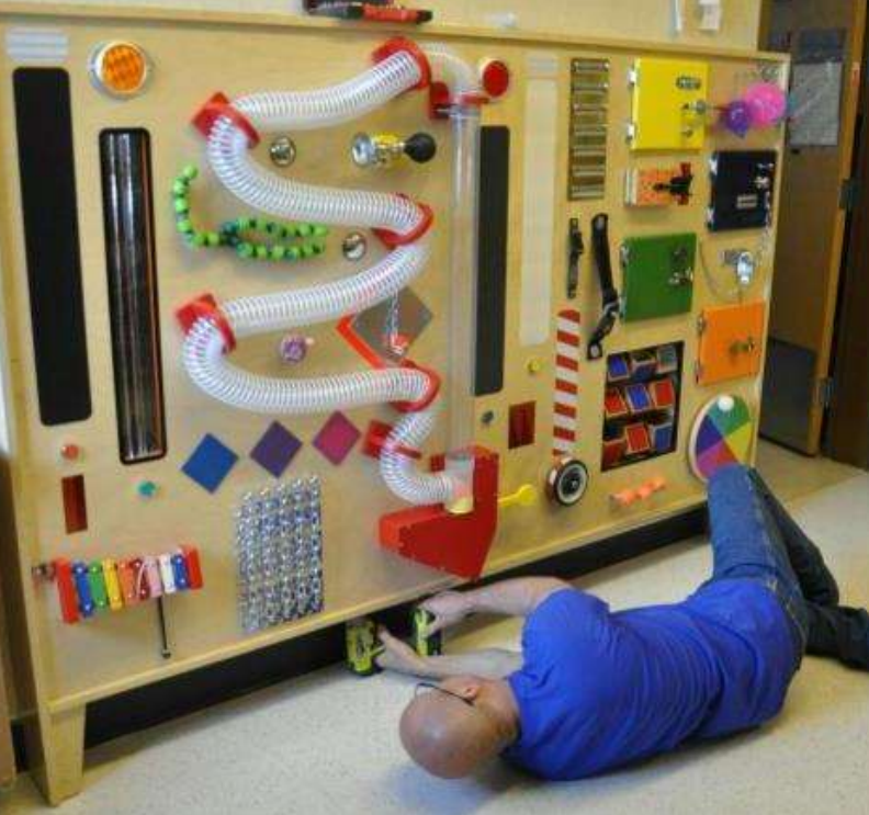 Man in a blue shirt assembling a large toy