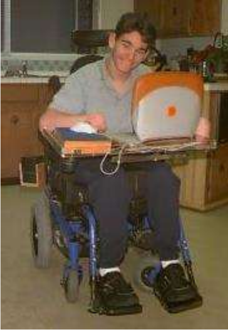 Man in a wheelchair using a Mac laptop