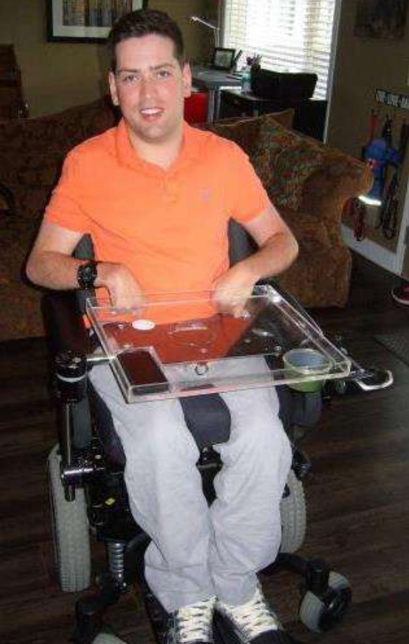Man in a wheelchair wearing an orange polo shirt