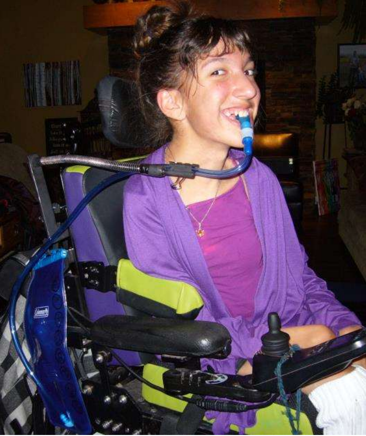 Girl in a wheelchair drinking water from a hydration pack