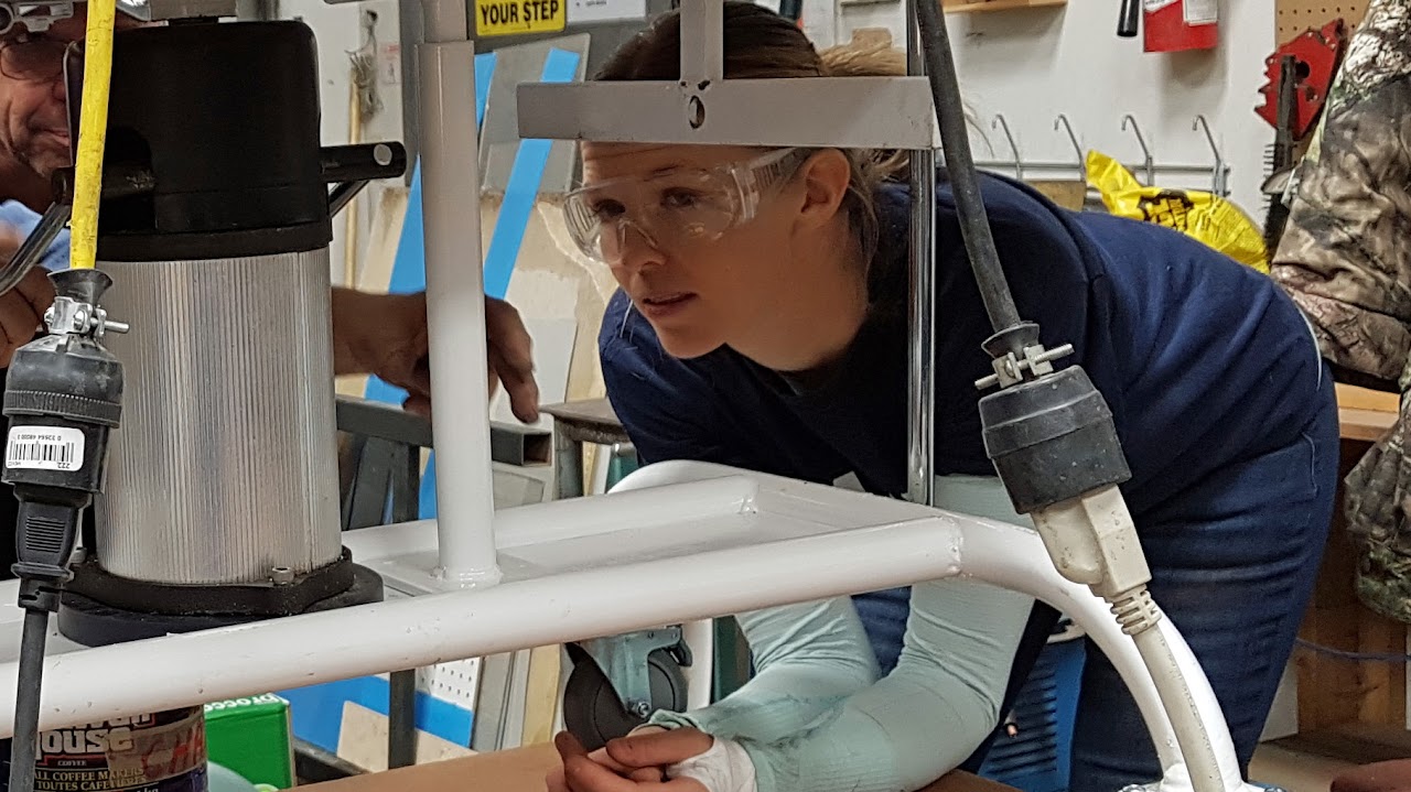 Woman in a workshop wearing safety glasses inspecting her project
